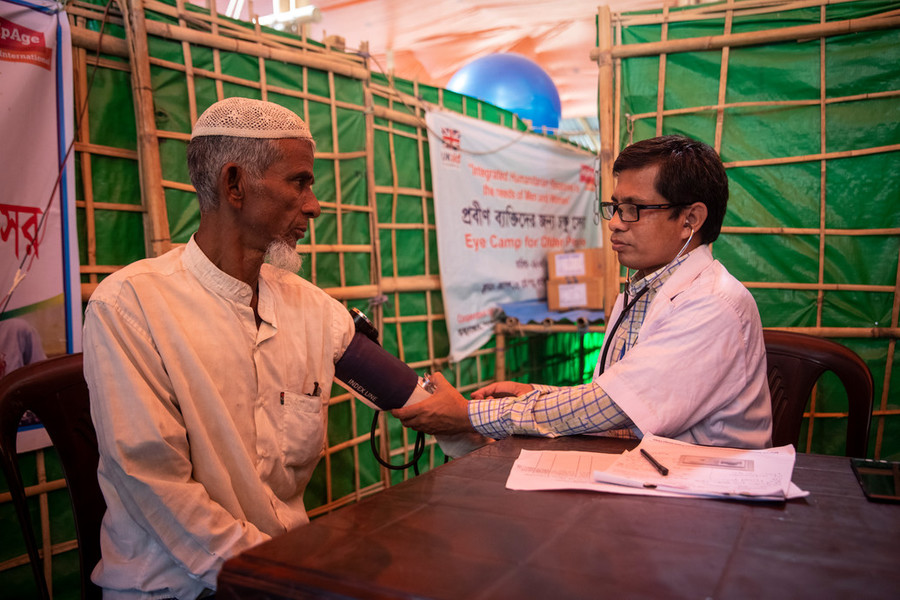 an older Rohingya man gets his blood pressure checked by a doctor at a refugee camp in Bangladesh. 
