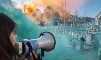 A protester speaks through a megaphone as smoke from coloured smoke bombs billows near people taking part in the annual May Day rally in Strasbourg, eastern France, on May 1, 2019.