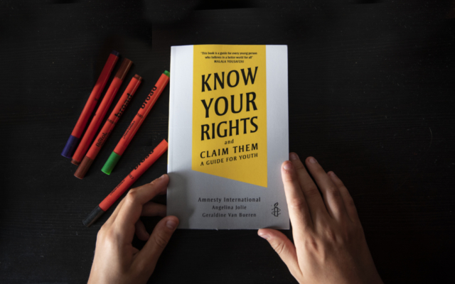 the book Know Your Rights, And Claim them is on a table next to a set of pens. 