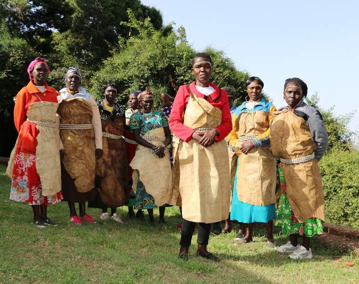 a group people who are members of the Sengwer indigenous community. They are all wearing colourful jackets and skirts and have a brown fabric that is held to them by a wooden beaded belt. 