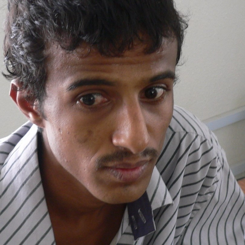 a portrait of Hafex Ibrahim. He is wearing a white and grey striped shirt. 